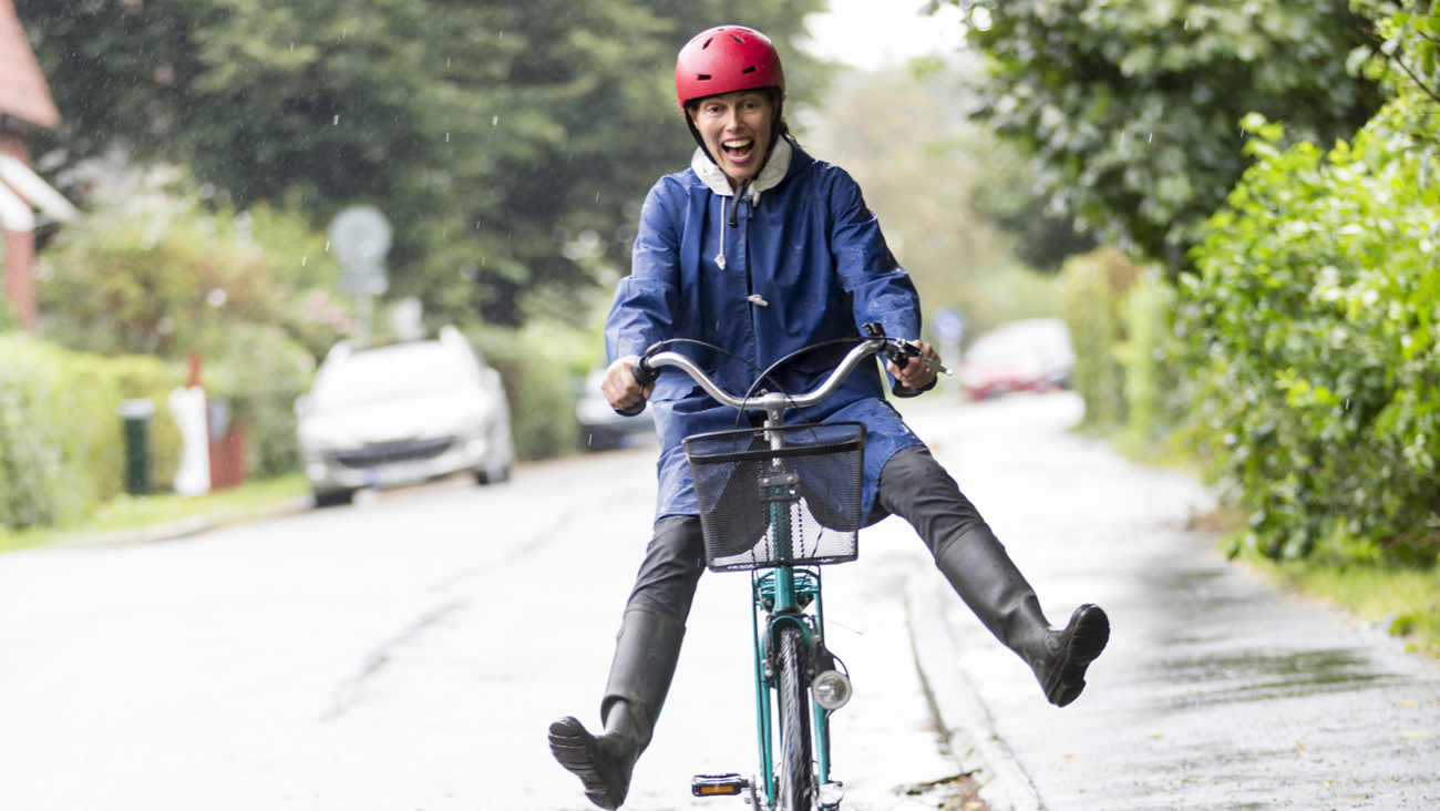 En glad kvinna sitter p&aring; en cykel.