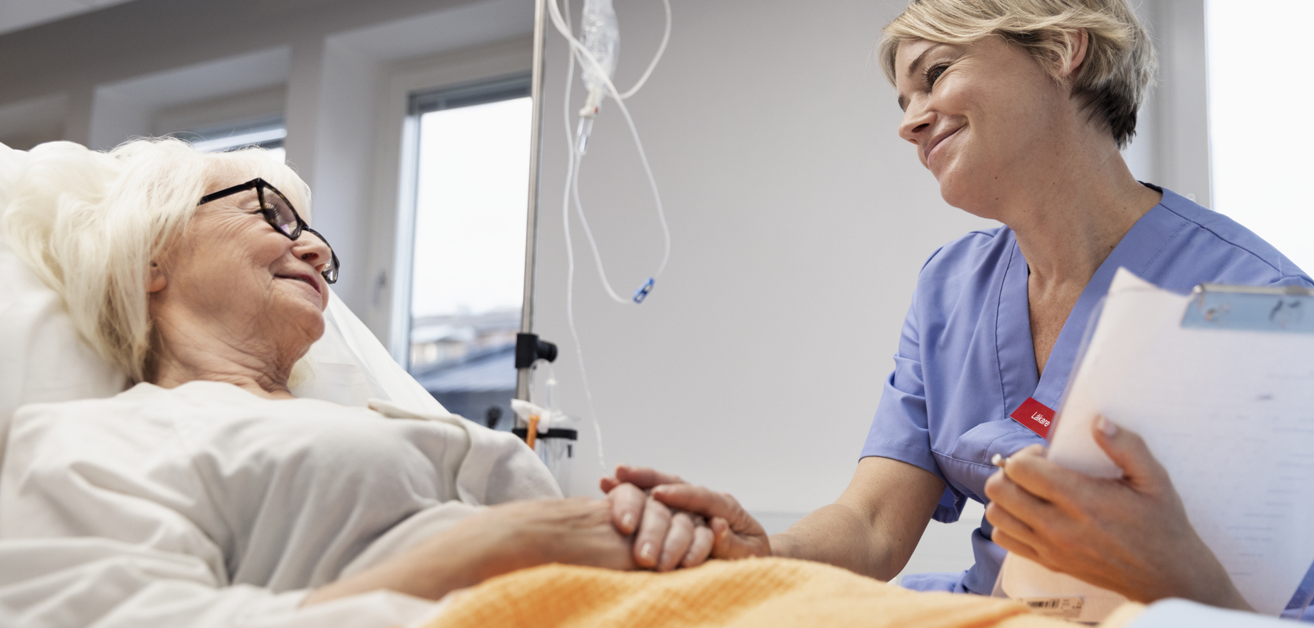 En personal tittar på en patient i en sjukhussäng