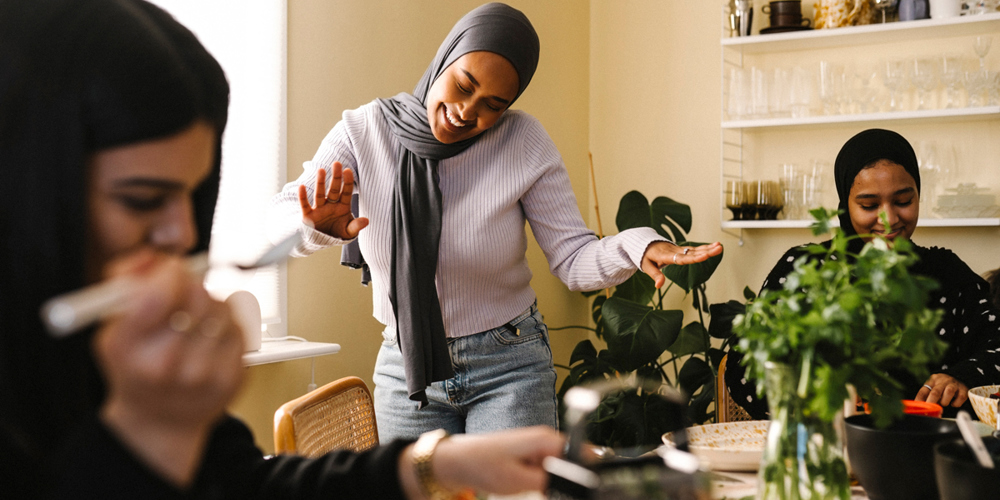 Fyra äldre damer sitter på en bänk på en tågperrong och skrattar.